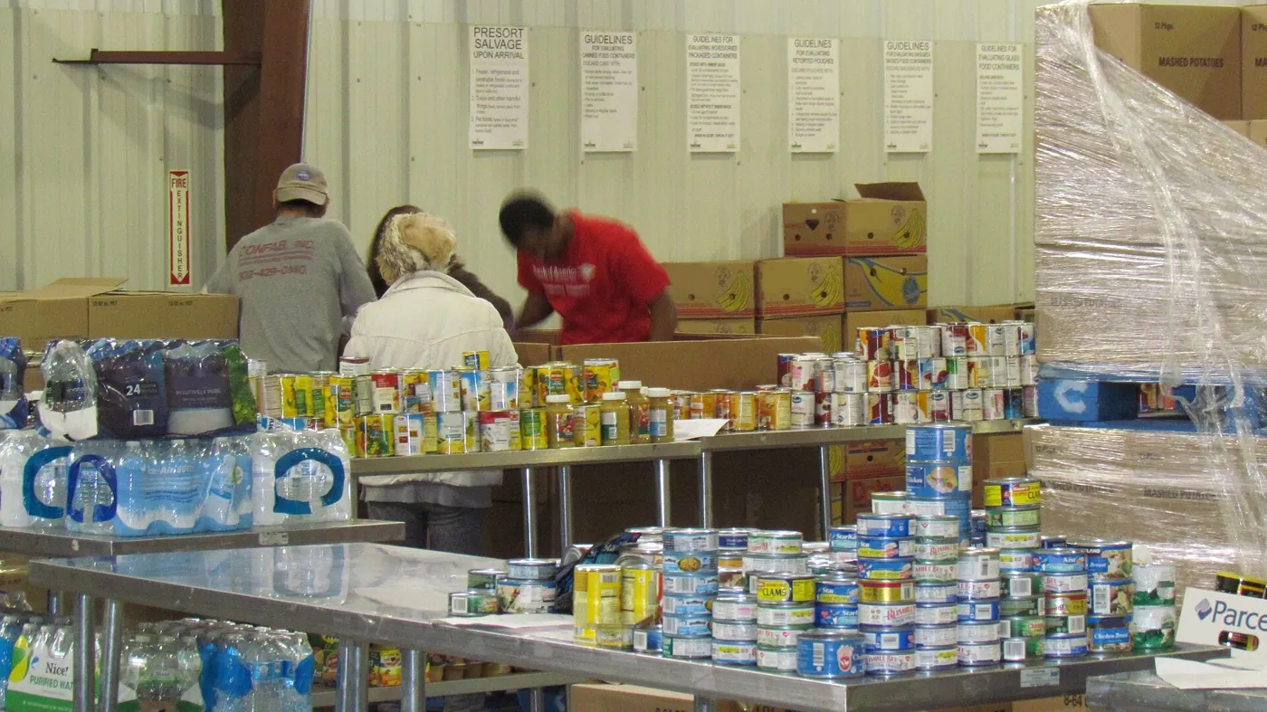 Volunteers sorting donated groceries at a food bank warehouse